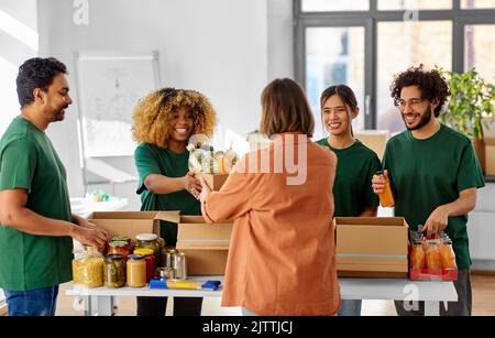 des bénévoles heureux emballant des aliments dans des boîtes de dons Banque D'Images