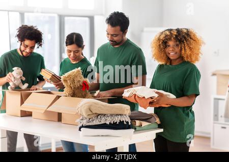 des bénévoles heureux emballant des produits dans des boîtes de dons Banque D'Images