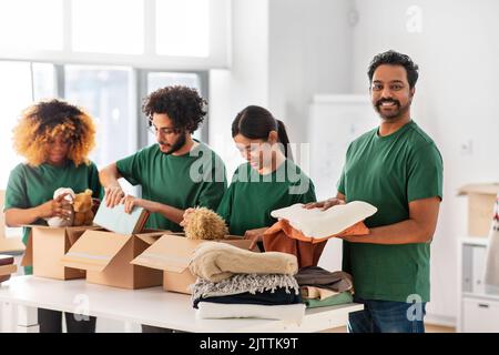 des bénévoles heureux emballant des produits dans des boîtes de dons Banque D'Images