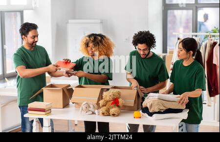des bénévoles heureux emballant des produits dans des boîtes de dons Banque D'Images