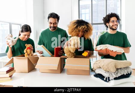 des bénévoles heureux emballant des choses dans des boîtes de dons Banque D'Images
