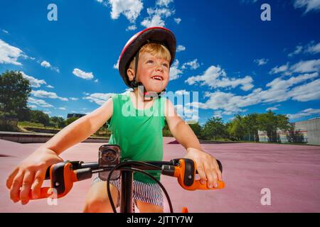 Garçon sur un petit vélo dans un casque, à cheval sur le portrait du parc Banque D'Images