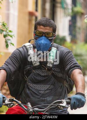 Black man livrant de la nourriture à vélo dans une rue à Rio de Janeiro, Brésil. Banque D'Images