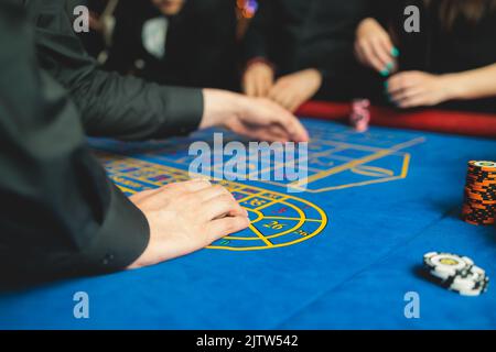 Table de casino vibrante avec roulette en mouvement, avec des jetons de casino, la main de croupier, l'argent de facture de dollar et un groupe de jeux riches Banque D'Images