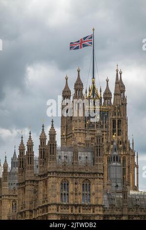 Londres, Angleterre, Royaume-Uni - 6 juillet 2022 : depuis la Tamise. Tour Victoria avec drapeau sur le dessus et garnitures dorées sur le palais de Westminster et hall sous la cl grise Banque D'Images