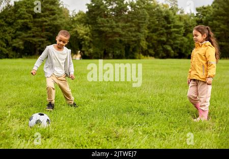 petits enfants avec le ballon jouant au football au parc Banque D'Images