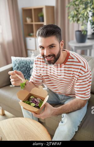 homme souriant mangeant des plats à emporter à la maison Banque D'Images