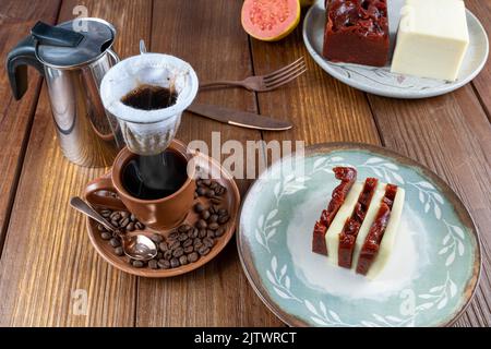 Tranches de fromage à la guava, doux et caillé, à côté des grains de café, d'une tasse et d'un filtre à café en tissu. Banque D'Images