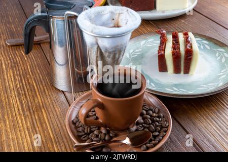 Tranches de fromage de goyave et de caillé. En premier plan flou, filtre à café en tissu sur tasse et grains de café. Banque D'Images