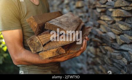 Un homme met le bois entre les mains d'une pile de bois pour une cheminée à la maison. Le concept de chauffage au bois et la crise énergétique Banque D'Images