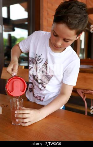 Garçon versant du jus dans le verre de la carafe dans le restaurant Banque D'Images