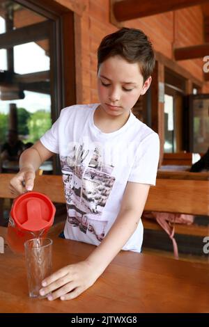 Enfant versant du jus dans le verre de la carafe dans le restaurant Banque D'Images