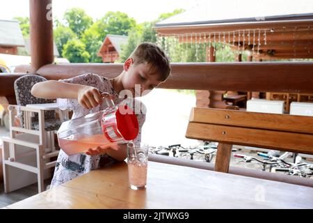 Enfant versant du jus dans le verre de la carafe dans le restaurant Banque D'Images