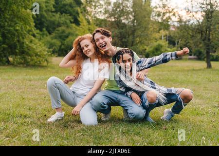 Blogueurs caucasiens appréciant le moment drôle en posant dans le parc de la ville, se détendre entouré par la nature verte. Communauté de jeunes, groupe. Heureux Banque D'Images