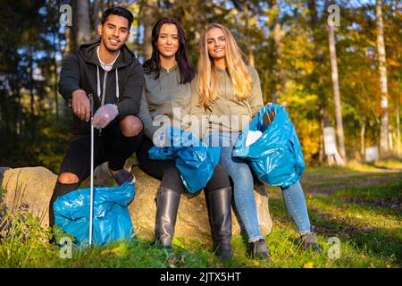 Bénévoles multiethniques dans l'équipe de protection de l'environnement assis avec des sacs à ordures Banque D'Images