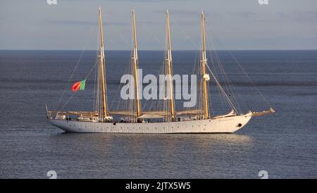 La goélette blanche SANTA MARIA MANUELA, qui renonce au drapeau du Portugal, ancrée au large de la côte, à la lumière du coucher du soleil, Angra do Heroismo, Terceira, Açores, Portugal Banque D'Images