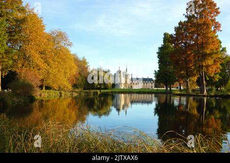 Vue sur le château de Chantilly reflétée dans la piscine entourée d'arbres de parc. Automne. France. Banque D'Images