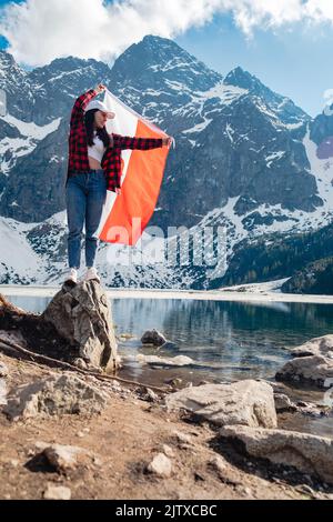 Une femme avec le drapeau de la Pologne est debout sur la rive d'un lac. Morskie Oko Banque D'Images