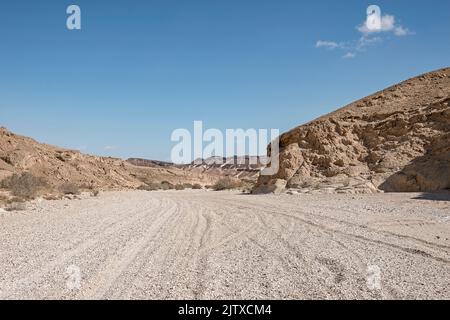 Lit de ruisseau Nahal Nekarot utilisé comme piste hors route sur la route des épices en Israël avec du sable blanc au premier plan et un fond bleu ciel Banque D'Images