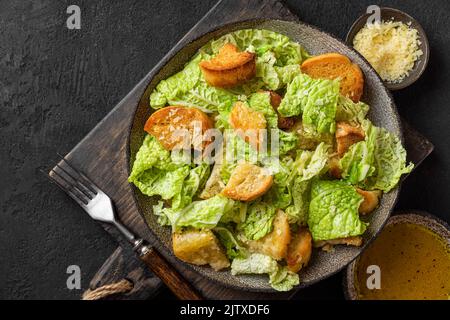 Délicieux plats savoureux. Salade César au parmesan et croûtons croustillants dans une assiette sur fond noir. Vue de dessus Banque D'Images