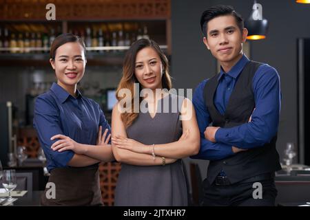 Happy Vietnamese restaurant manager, waitress and barman Banque D'Images