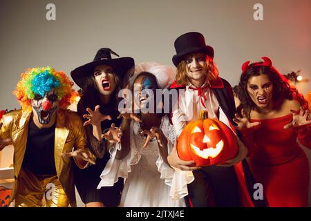 Groupe de personnes vêtues de costumes de fête effrayants ayant le plaisir à la fête d'Halloween Banque D'Images