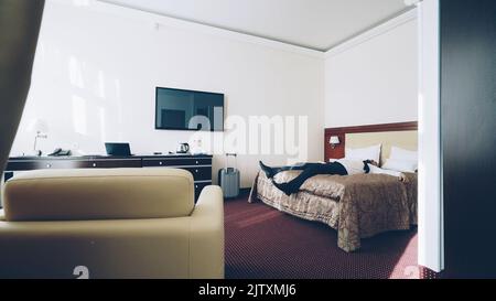 Homme d'affaires avec des bagages couchés sur le lit détendu souriant. Concept de voyage, d'affaires et de personnes. Banque D'Images