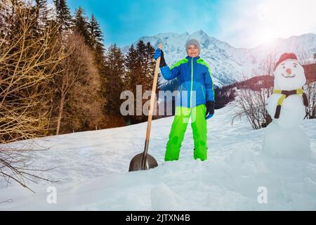 Stand pour enfants avec pelle neige propre et construction d'un bonhomme de neige Banque D'Images