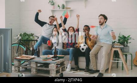 Des amis heureux avec des drapeaux portugais regardant le championnat sportif à la télévision ensemble à la maison à l'intérieur et heureux de gagner de l'équipe préférée Banque D'Images