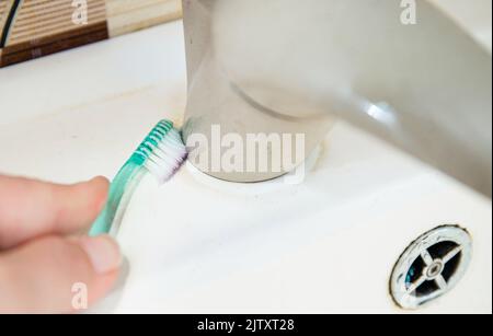 Vue rapprochée d'une femme nettoyant les mains lavabo de salle de bains avec brosse à dents. Sac de nettoyage pour la maison, s'adapte aux petits espaces pour nettoyer les moisissures et la saleté. Banque D'Images