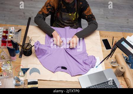 Vue rognée de l'artisan afro-américain travaillant avec un t-shirt en atelier, image de stock Banque D'Images