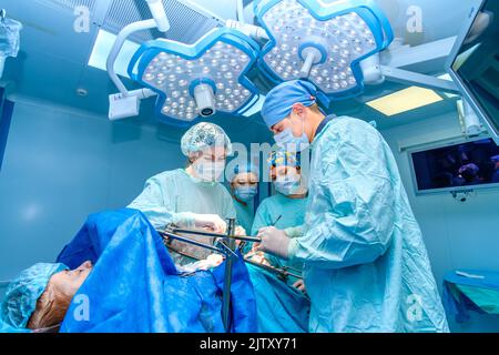 Moscou. Russie. 10 août 2022. Une équipe de chirurgiens intervient sur un patient allongé sur la table d'opération. Traitement chirurgical de maladies coloproctologiques. Banque D'Images