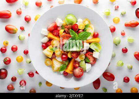Salade de différentes variétés, mélange de tomates rouges, jaunes, vertes et noires, fromage mozzarella et basilic. Sales de Caprese aux tomates fraîches et colorées. Photographie alimentaire Banque D'Images