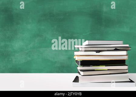 pile de livres sur le bureau blanc contre le tableau vert avec espace de copie, éducation et concept d'école Banque D'Images