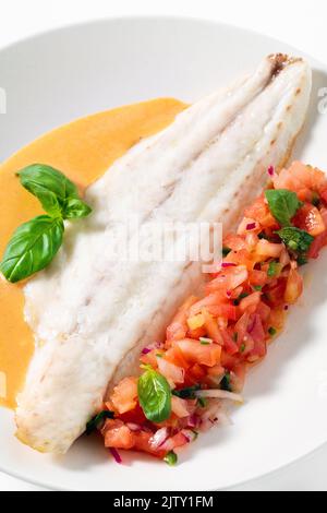 Filet de bar grillé avec salade de tomates au basilic et sauce sur fond blanc Banque D'Images