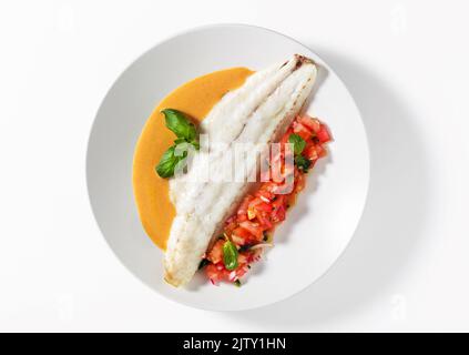 Filet de bar grillé avec salade de tomates au basilic et sauce sur fond blanc Banque D'Images