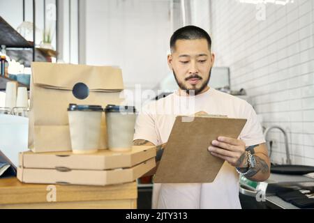 Un employé de café masculin reçoit des commandes de plats à emporter en place Banque D'Images