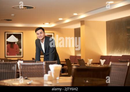 Jeune et souriant, le propriétaire d'un restaurant asiatique vérifie les tables Banque D'Images