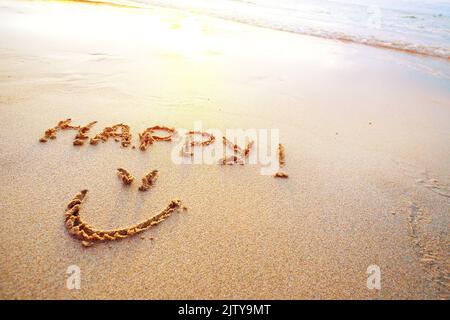 Lettres joyeuses manuscrites dans le sable sur la plage Banque D'Images