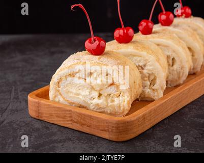 dessert meringue à la poire fraîche, décoré de cerises sur fond sombre dans un café. Copier l'espace Banque D'Images