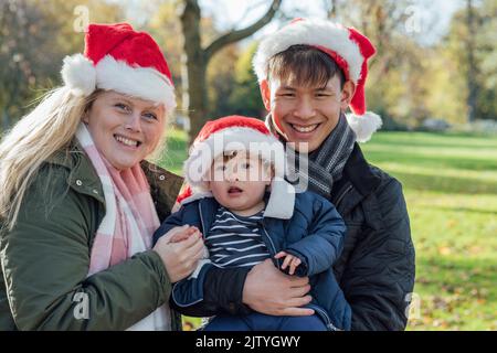 Une famille se tenant ensemble en plein air dans la nature à Northumberland, dans le nord-est de l'Angleterre pendant l'automne. Ils portent tous des chapeaux de père noël tout en regardant le TH Banque D'Images