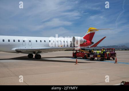 Équipage au sol, manutentionnaires de bagages avec chariots chargés de valises par un avion de Madrid à Grenade, un avion Bombardier CRJ1000, Espagne Banque D'Images