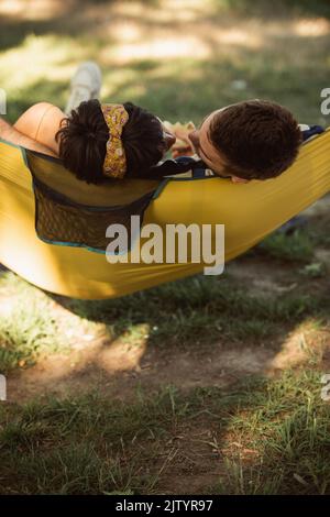Beau couple qui va pour un baiser tout en se relaxant sur un hamac jaune dans le parc Banque D'Images