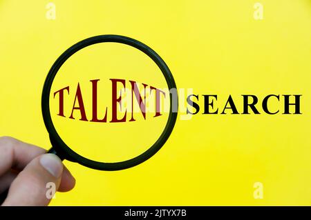 Gros plan sur le texte de recherche de talents à l'aide d'une loupe sur fond de couverture jaune. Banque D'Images