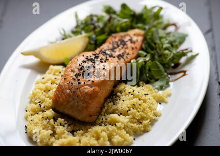 saumon cuit au four avec salade d'épinards et couscous Banque D'Images
