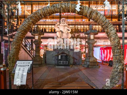 tokyo, japon - décembre 15 2021 : statue en pierre du Dieu chanceux Daikokuten illuminée la nuit pendant le rituel de purification chinowa-kuguri à l'aide d'un c Banque D'Images