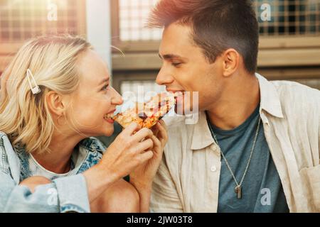 couple heureux de manger de la pizza à l'extérieur Banque D'Images