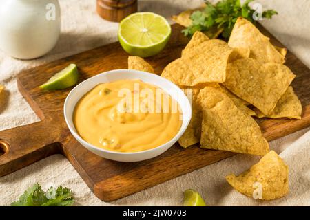Trempette au fromage Queso jaune maison avec chips de tortilla et citron vert Banque D'Images