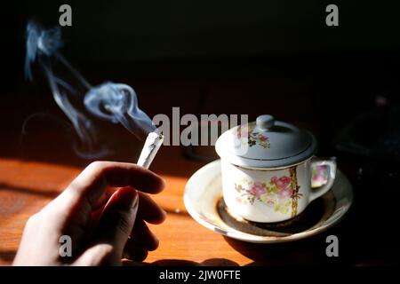 Cigarettes roulées à la main avec une tasse de café traditionnelle sur une table en bois Banque D'Images