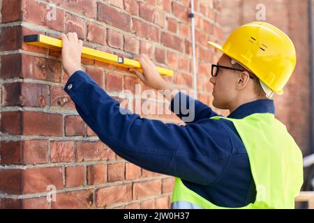 construction mâle avec mur de mesure de niveau Banque D'Images